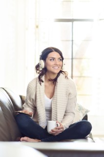 Caucasian woman sitting on sofa listening to headphones