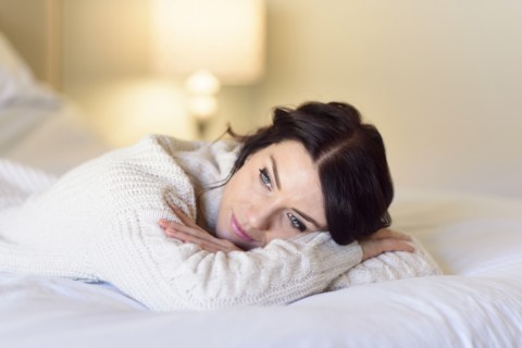 Caucasian woman daydreaming on bed
