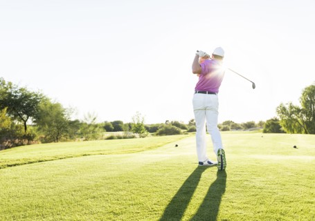 Hispanic golfer teeing off on golf course