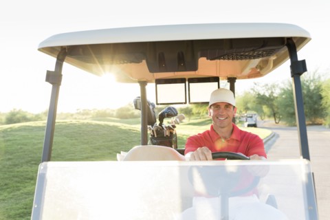 Portrait of Hispanic golfer driving golf cart