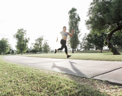 Hispanic woman running on path in park
