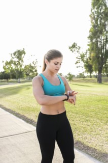 Hispanic woman checking the time on wristwatch in park