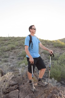 Hispanic hiker holding walking sticks on hill