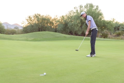 Caucasian golfer putting on golf course