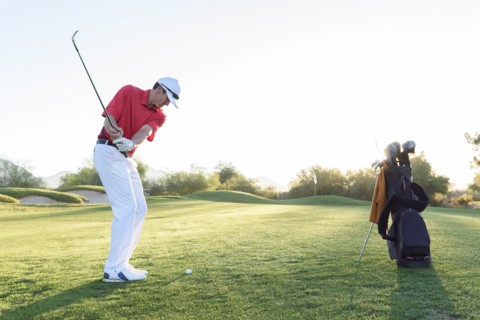 Hispanic man hitting ball on golf course