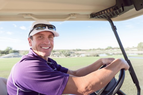 Portrait of smiling Hispanic man driving golf cart