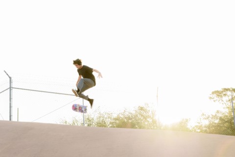 Hispanic man performing mid-air trick on skateboard