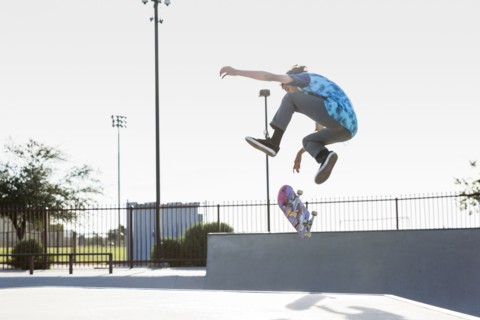 Hispanic man performing mid-air trick on skateboard
