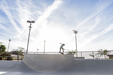 Hispanic man riding skateboard at skate park