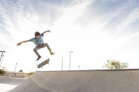 Hispanic man performing mid-air trick on skateboard