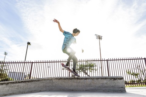 Hispanic man riding skateboard in skate park
