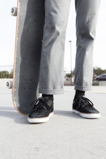 Legs of Hispanic man holding skateboard