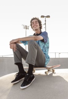 Portrait of smiling Hispanic man sitting on skateboard