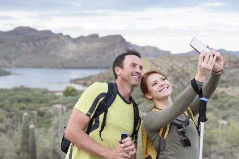 Hikers posing for cell phone selfie in desert