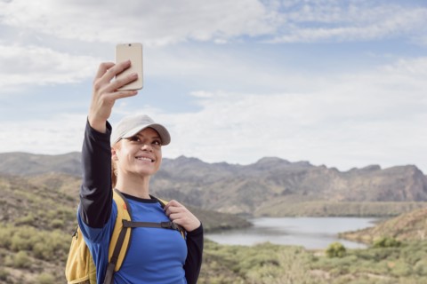 Caucasian woman posing for cell phone selfie in desert