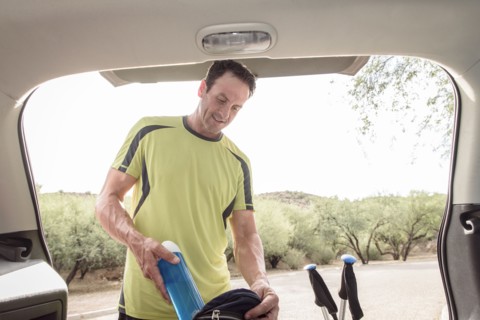 Hispanic man pulling water bottle from backpack in car