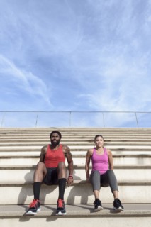 Man and woman doing triceps dips on bleachers