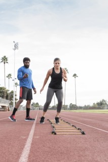 Trainer watching woman running ladder