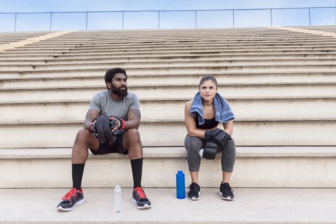 Trainer and woman resting on bleachers