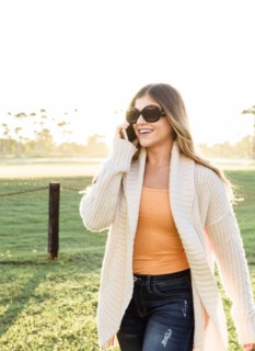 Smiling Hispanic woman wearing sunglasses talking on cell phone