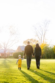 Caucasian mother and father walking in field with son