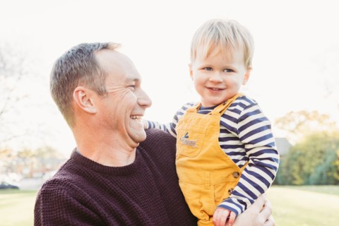 Laughing Caucasian father holding son