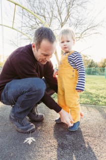 Caucasian father adjusting pants for son