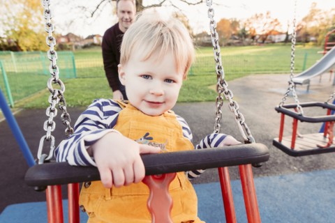 Caucasian father pushing son on swing