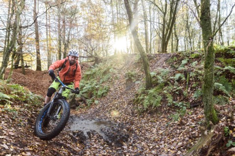 Caucasian man steering bicycle around mud puddle