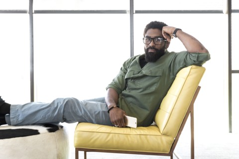 Black man sitting in chair holding cell phone
