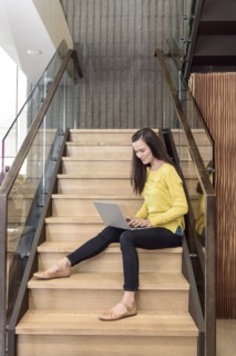 Mixed race woman sitting on staircase using laptop
