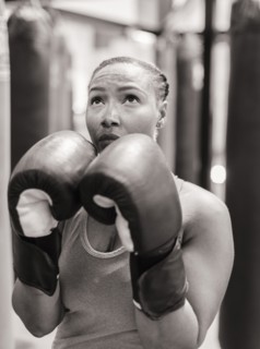 Portrait of Black woman wearing boxing gloves looking up