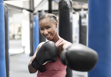 Portrait of smiling Black woman wearing boxing gloves in gymnasium