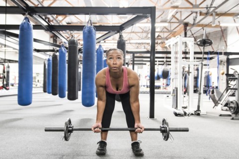Black woman lifting barbell in gymnasium