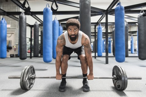 Black man lifting barbell in gymnasium
