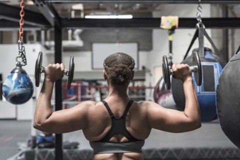 Black woman lifting dumbbells in gymnasium