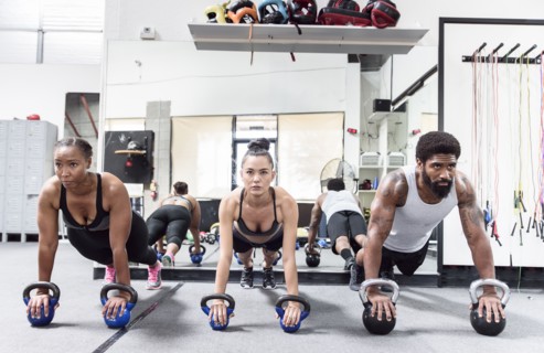 Man and women doing push-ups with kettlebells