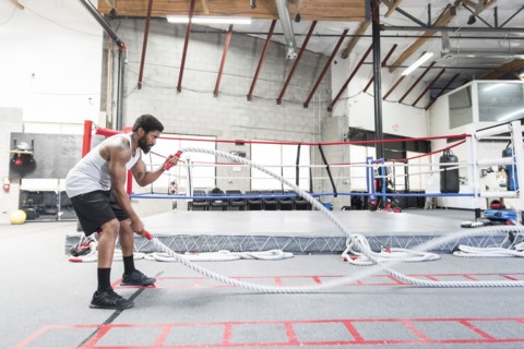 Black man lifting heavy ropes in gymnasium