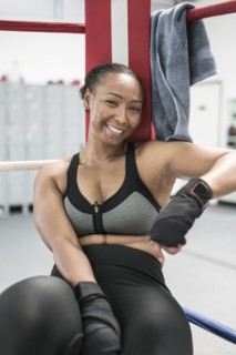 Black woman leaning in corner of boxing ring
