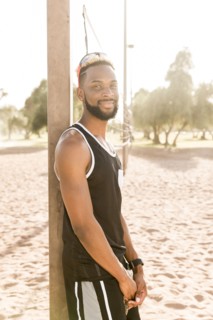 Portrait of smiling black man leaning on beach volleyball net