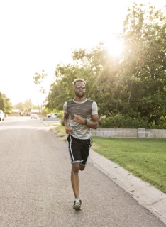 Black man running on street in neighborhood