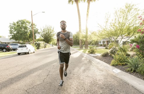 Black man running on street in neighborhood