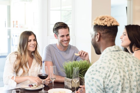 Friends smiling and talking with wine and snacks