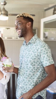 Man holding cold drink laughing outdoors