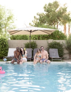 Smiling friends sitting and relaxing poolside