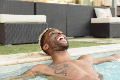 Smiling Black man relaxing in swimming pool