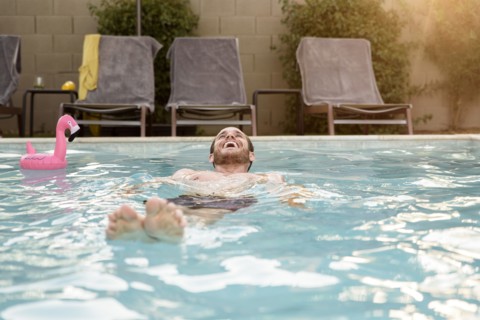 Smiling Caucasian man floating in swimming pool
