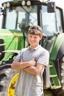 Confident Caucasian man standing near tractor