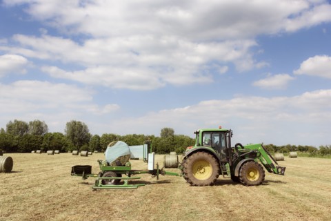 Caucasian man driving tractor baling hay