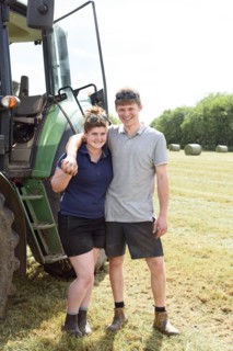 Smiling Caucasian couple posing near tractor